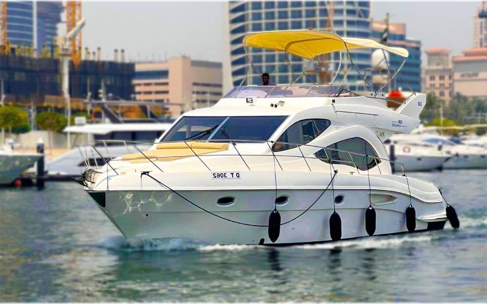 White 48ft Emerald Majesty luxury yacht with a yellow sun canopy cruising in Dubai.