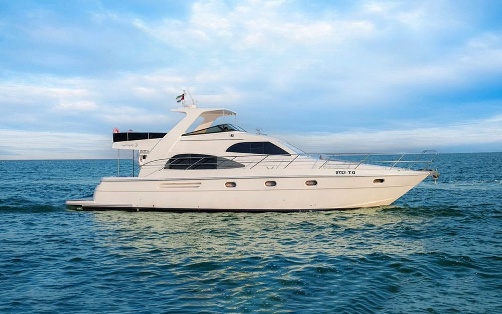 Side profile of the 55FT Blue Infinity yacht (DT 1275) cruising on the open blue sea under a cloudy sky.