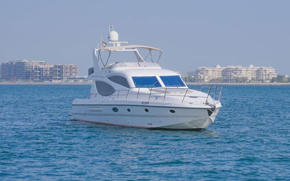 Profile view of the 70FT Alshali luxury yacht (DT 2576) cruising in the open water with a tan bimini top.